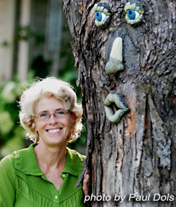 Colleen posing in her yard near a tree face that was given by a friend.
